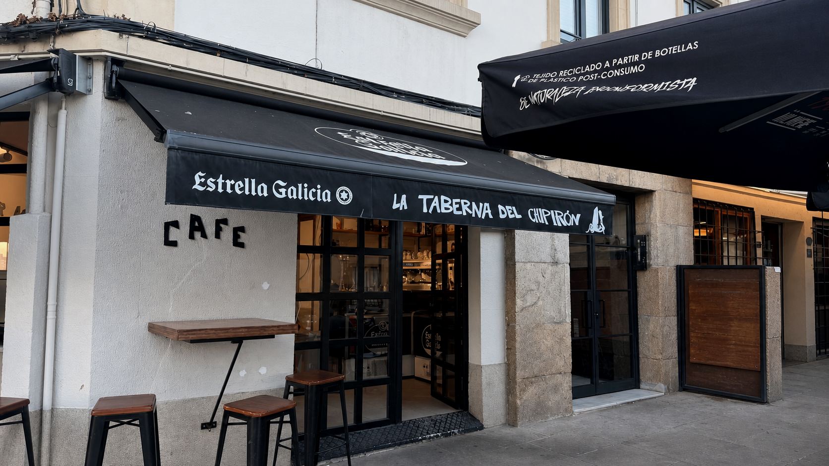 Fachada blanca con toldo negro y acceso acristalado de La Taberna del Chipirón